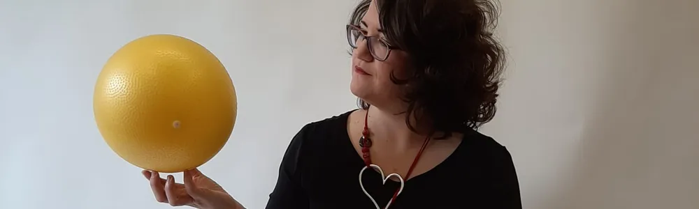 Donna seduta a terra che tiene una palla in mano e la guarda
