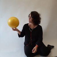 Donna seduta a terra che tiene una palla in mano e la guarda