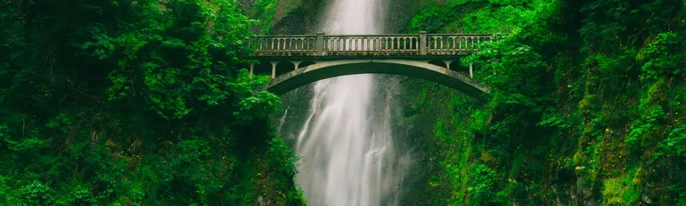 Ponte in montagna che attraversa una fonte d'acqua che forma una cascata