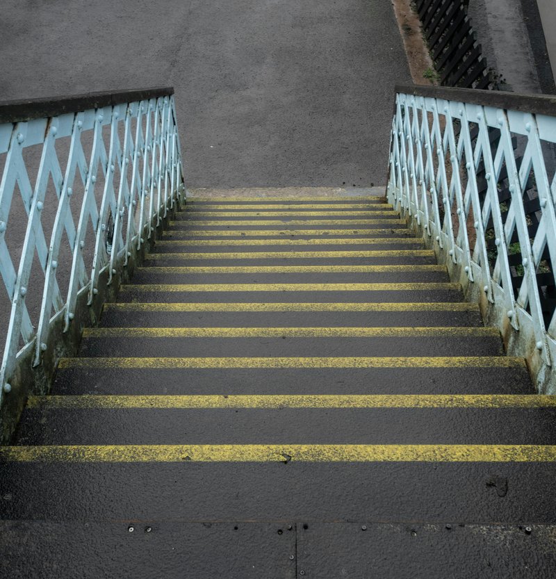 Rampa di scale in discesa, con corrimani bianchi e neri