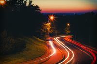 strasa al tramonto tra le colline con lucie delle auto in passaggio veloce